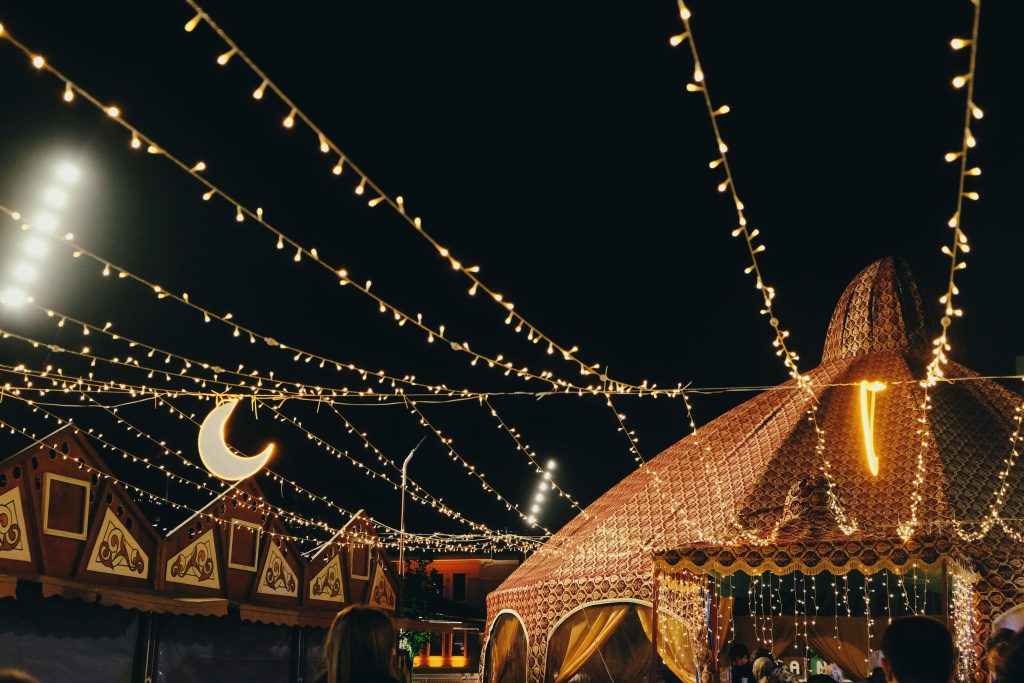 A lively night festival scene with decorative tents and string lights creating a festive atmosphere.